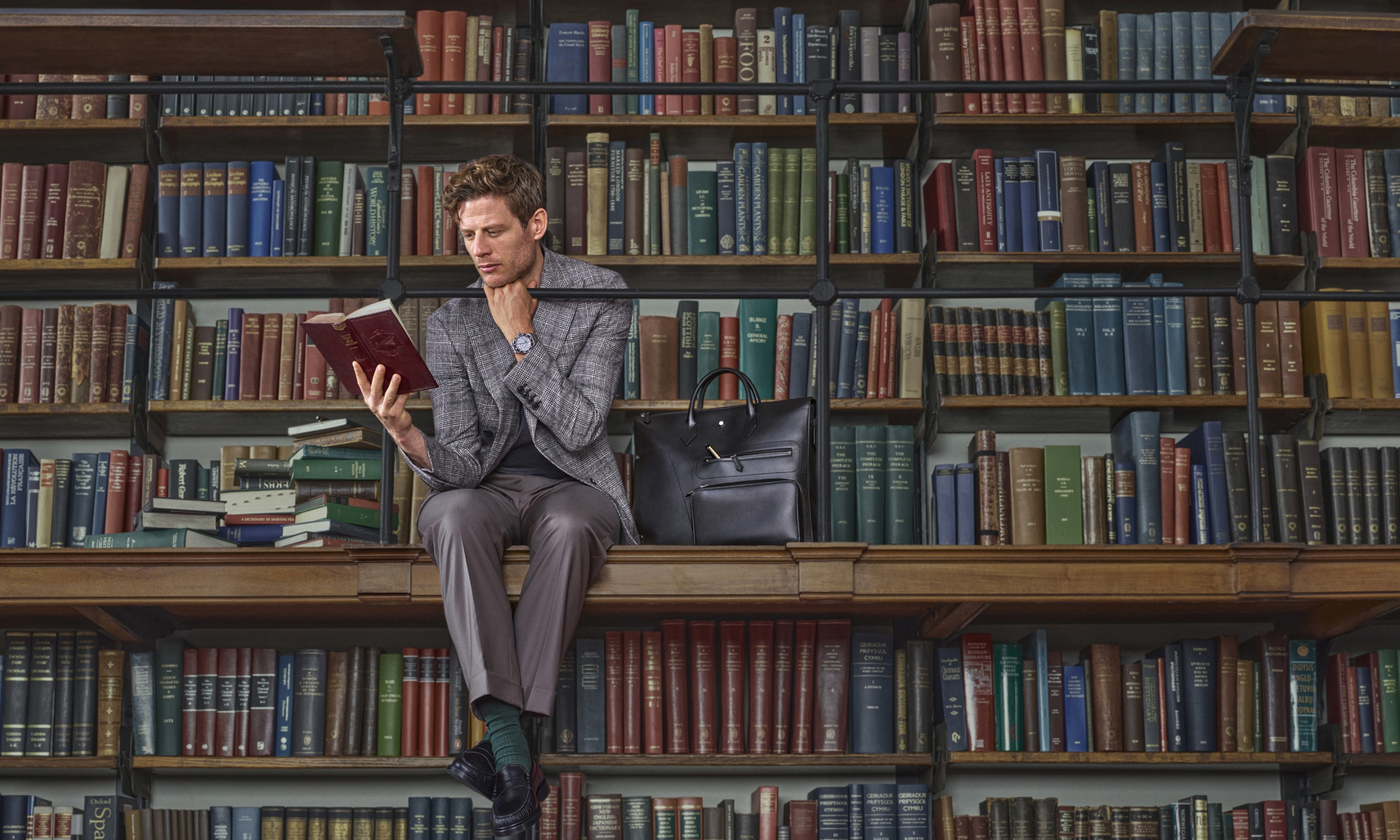 James Norton in a library reading a book