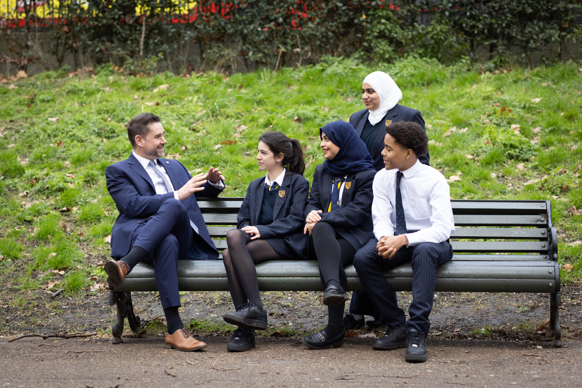Male teacher talking to pupils on bench